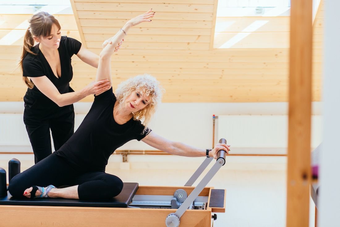 An instructor helping an older client with a supported stretch