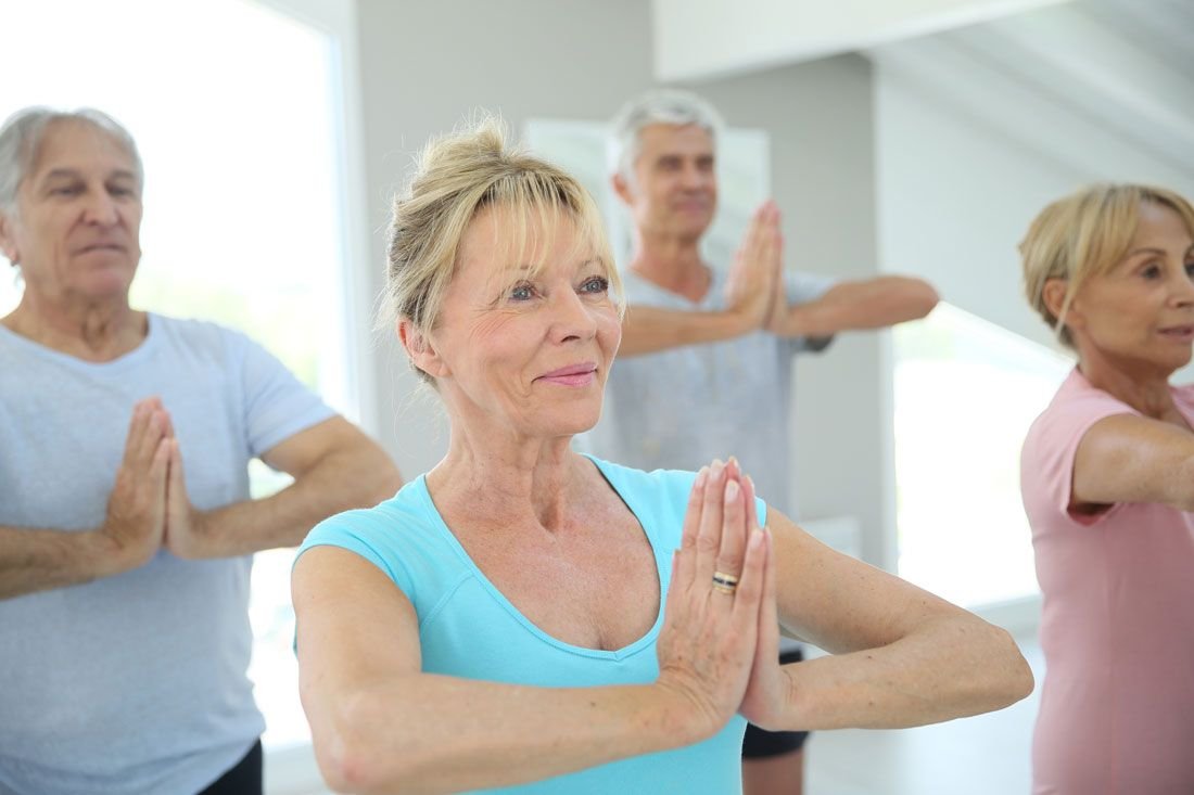 A group of older adults doing a standing stretch together