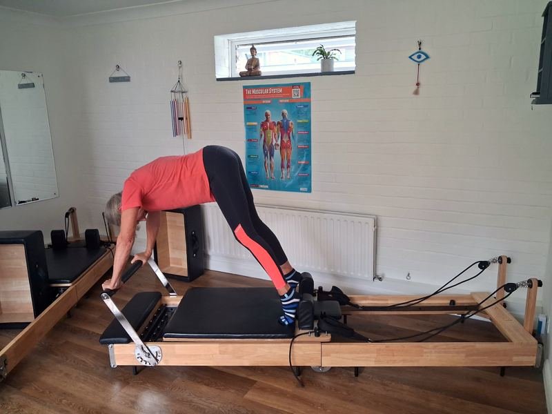 A client lifting her hips into a pike on the reformer carriage