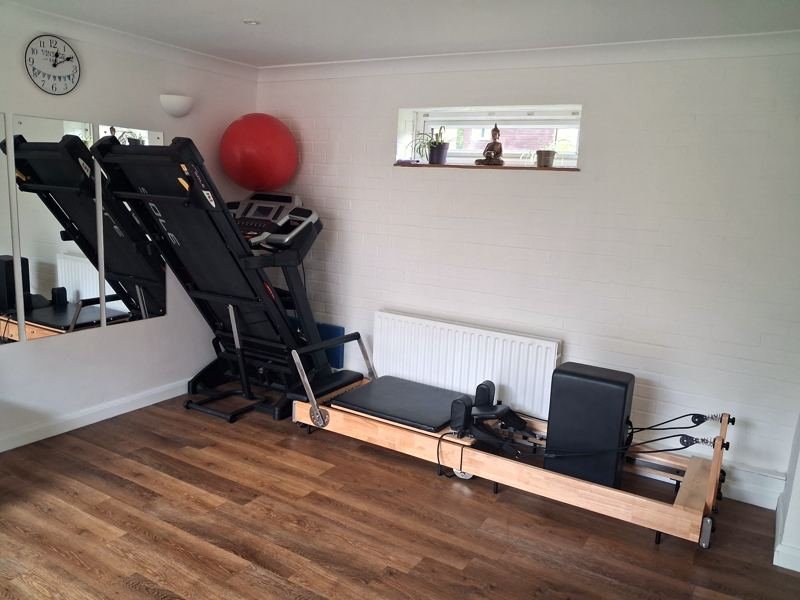 The studio with a reformer, a treadmill and a gym ball by the window